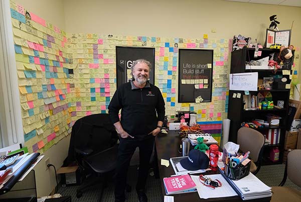 David Eyman in his office with 100s of post-it notes taped to the walls