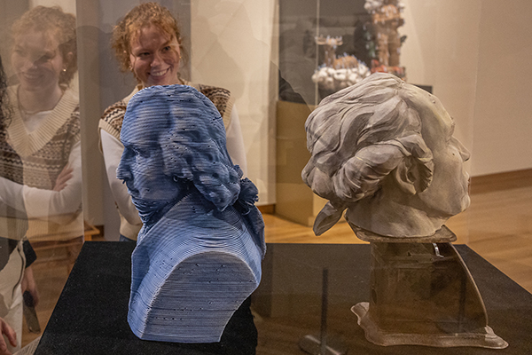 Two ceramic busts in the art museum with a woman looking through the glass case at them