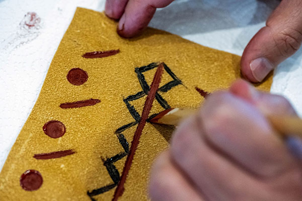 A participant paints a painted hide bag using egg yolk and mineral pigments at the Reclaiming Stories Learning Lab in the summer of 2022. Photo by Doug Peconge, Miami Tribe of Oklahoma