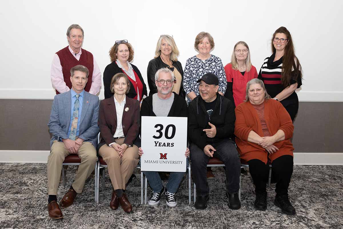 A group of 11 Miami employees pose with a 30 years of service sign in the Dolibois room