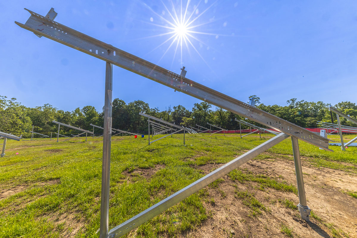 Solar panel racks on the Thomson field with a sunspot overhead